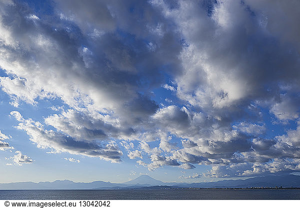 Low angle view of cloudy sky over sea and Mount Fuji during winter