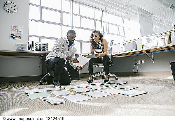 Low angle view of colleagues arranging documents on floor in office