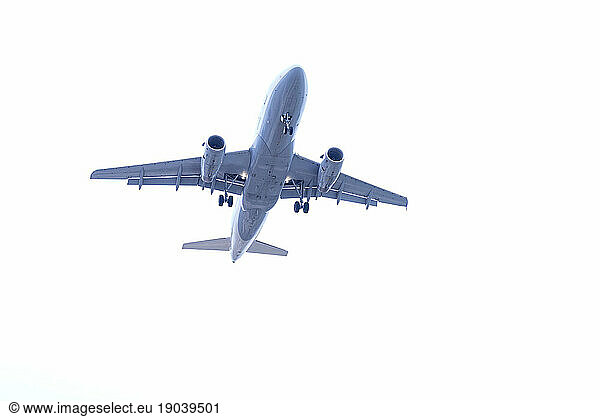 Low angle view of commercial airplane flying in sky with landing gear ready to take off at airport
