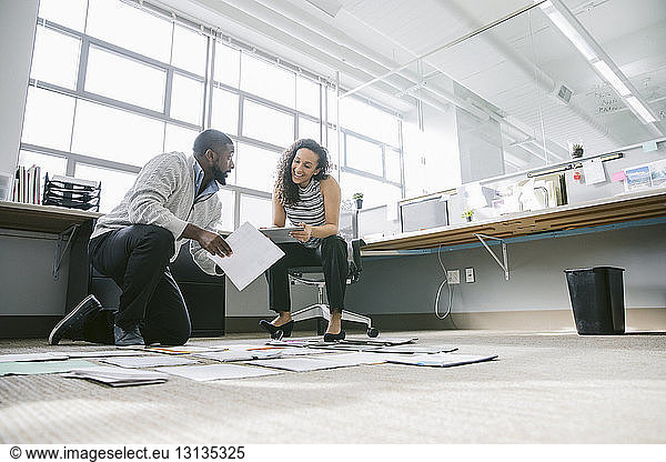 Low angle view of coworkers arranging documents on floor in office