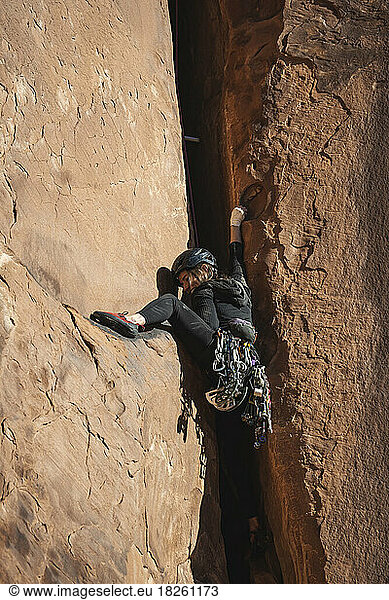 Low angle view of determined woman climbing desert rock