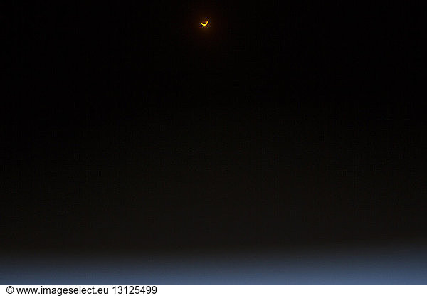 Low angle view of eclipse moon against clear sky at night