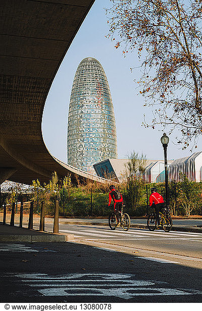 Low angle view of friends cycling against Torre Agbar