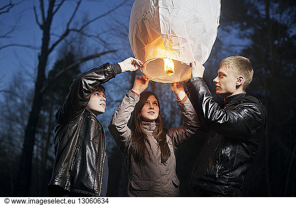 Low angle view of friends holding illuminated paper lantern