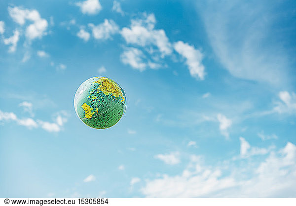 Low angle view of globe in mid-air against blue sky