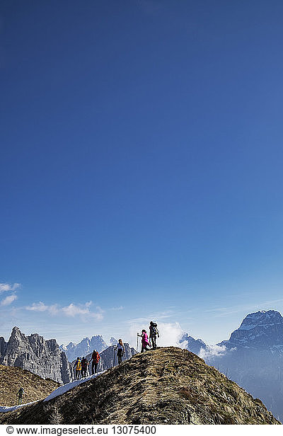Low angle view of hikers on mountain against blue sky