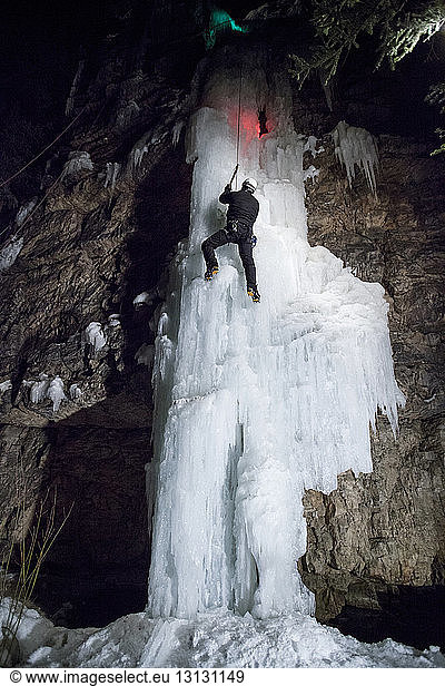 Low angle view of ice climber climbing on frozen waterfall