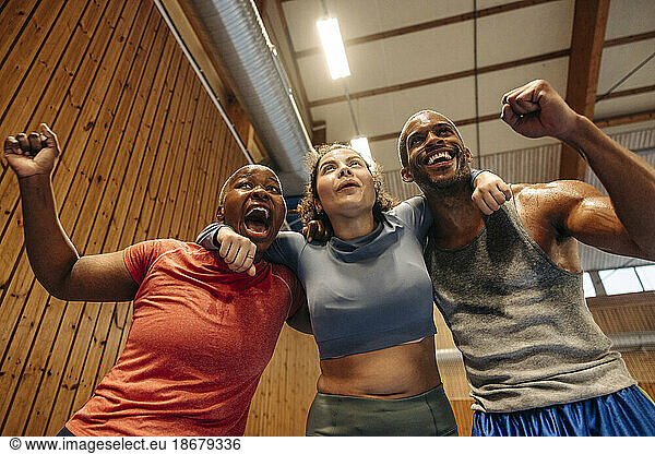 Low angle view of male and female athletes cheering together at sports court