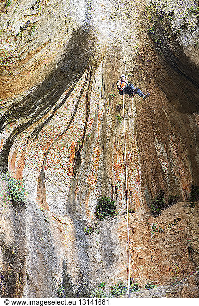 Low angle view of man rappelling from rock