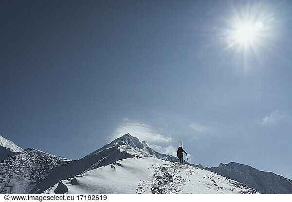 Low angle view of man splitboarding against sky during sunny day