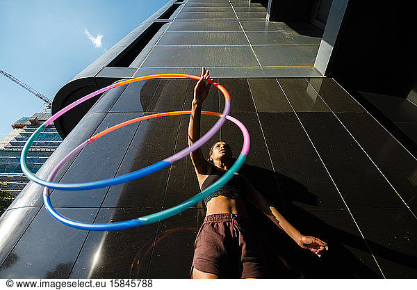 Low angle view of mixed race woman performing Hula Hoop dance in city