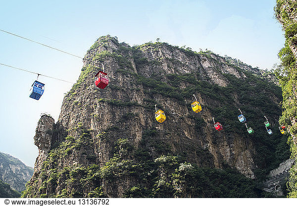 Low angle view of overhead cable cars against mountains
