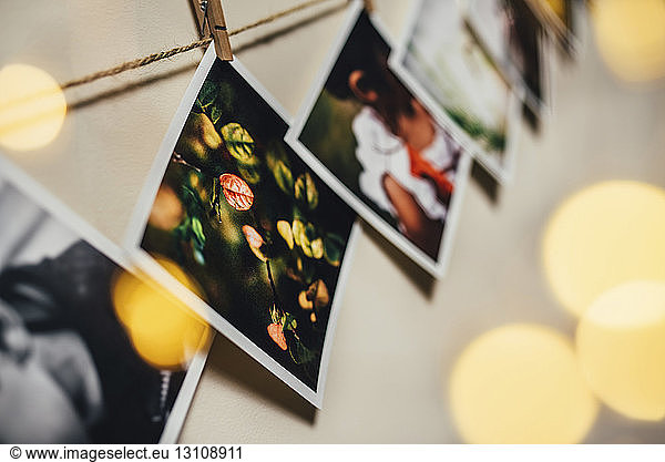 Low angle view of photographs hanging on rope against wall