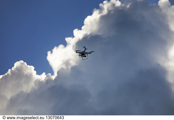 Low angle view of quadcopter against cloudy sky