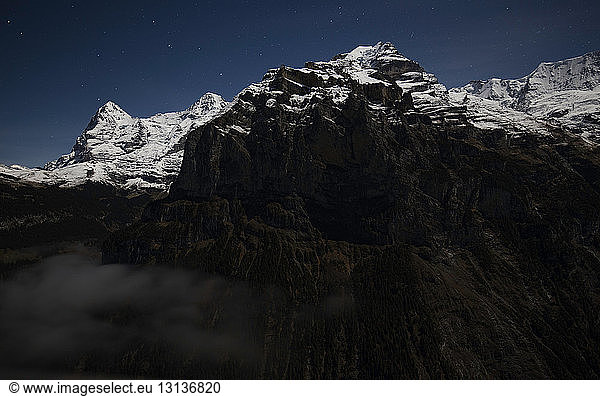 Low angle view of snowcapped mountain against sky at night