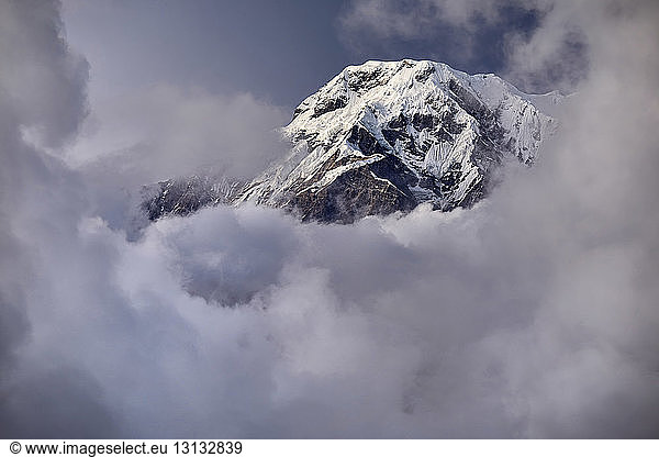 Low angle view of snowcapped mountain amidst cloudy sky
