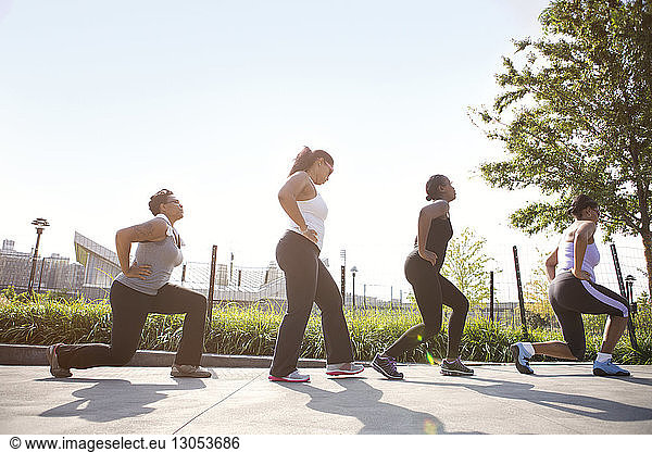 Low angle view of sportswomen exercising against sky on sunny day