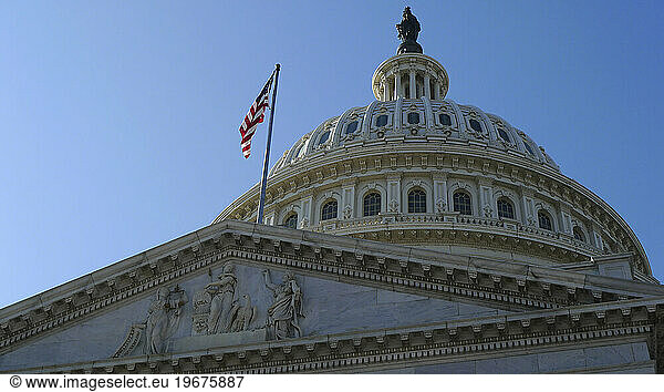 Low angle view of the historic landmkark  the Capitol building in Washington DC  flag flying  a dome and statue.