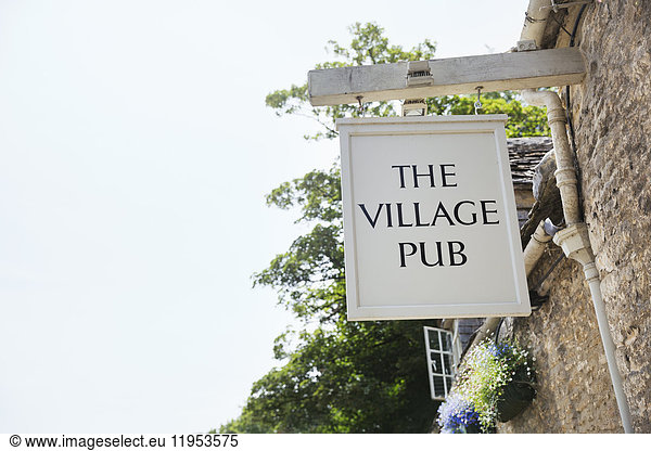 Low angle view of white wooden village pub sign.