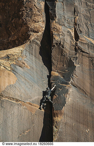 Low angle view of woman climbing rock formation at Bride Canyon