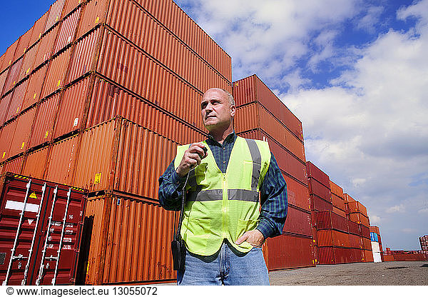Low angle view of worker standing against cargo containers