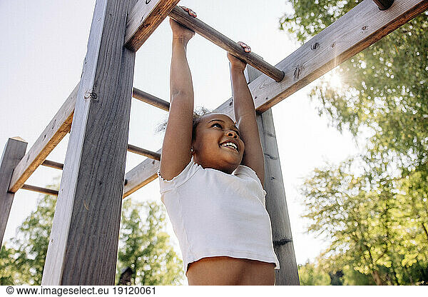 Low Angle View von lächelnden Mädchen hängen  während tun Monkey Bars im Sommerlager