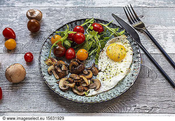 Low carb breakfast with fried egg  mushrooms  rocket and tomatoes