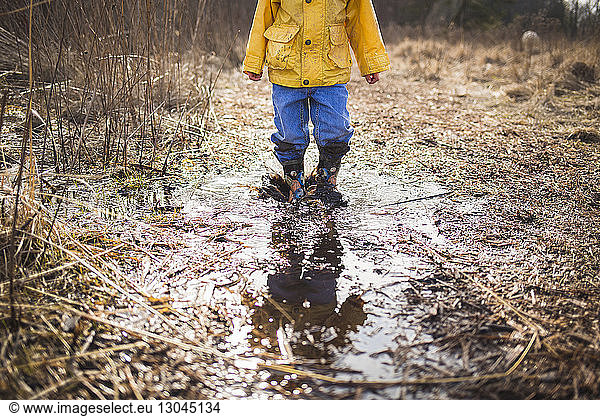 Low section of boy standing in dirty puddle