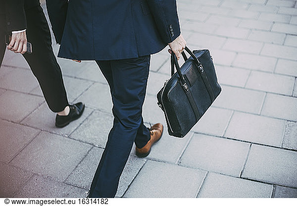 Low section of business colleagues walking on sidewalk