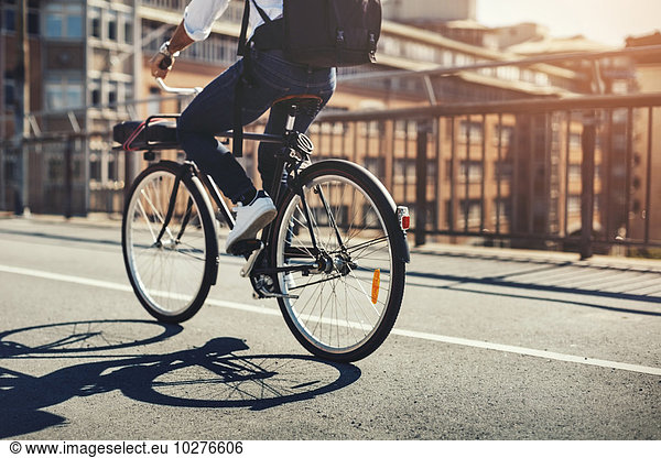 Low section of businessman riding bicycle on bridge in city