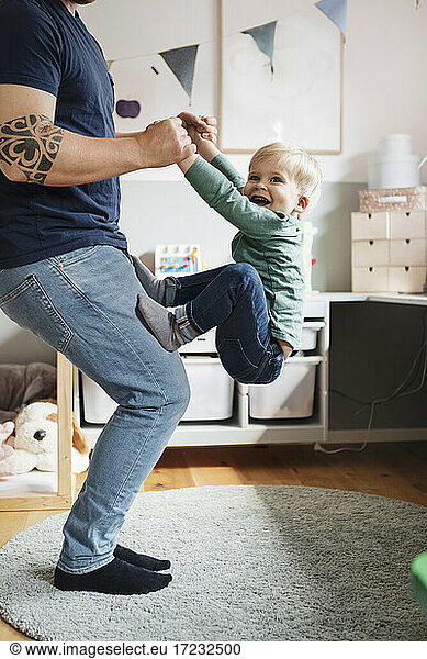 Low section of father playing with son at home