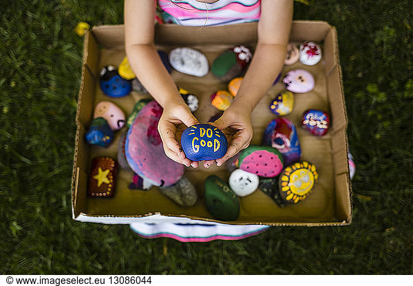 Low section of girl holding painted stones at park