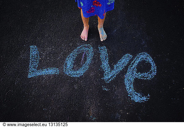 Low section of girl standing by love text on road