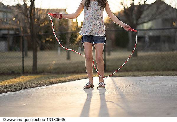 Low section of girl with jump rope at playground