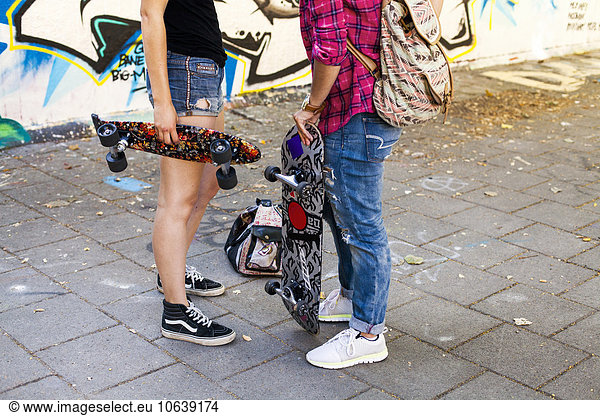 Low section of girls holding skateboards standing on street