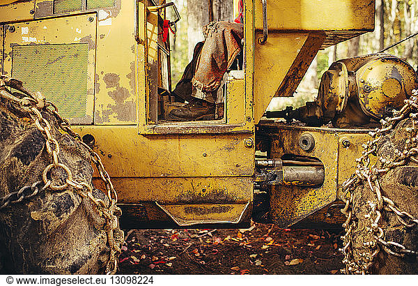 Low section of lumberjack sitting old construction vehicle in forest