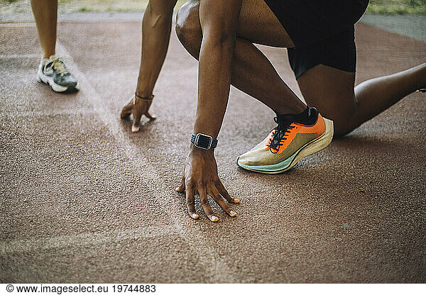 Low section of man kneeling at starting line on running track