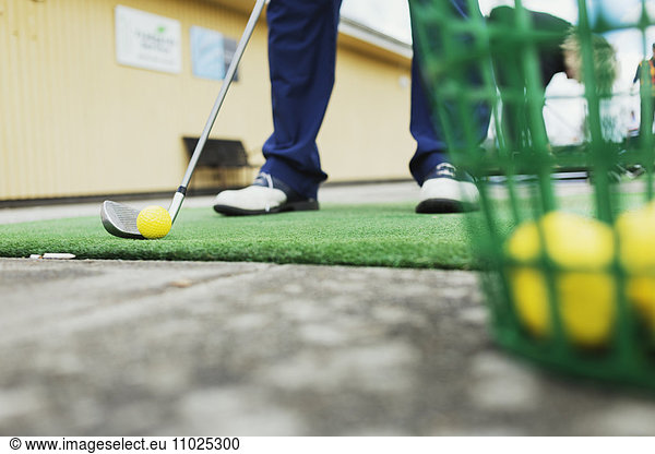 Low section of man playing golf at driving range