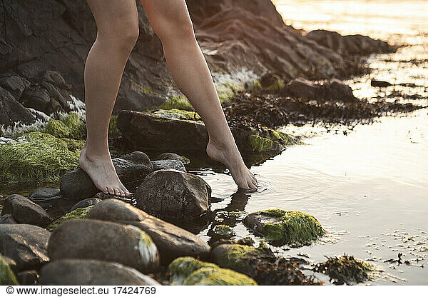 Low section of woman putting foot in sea