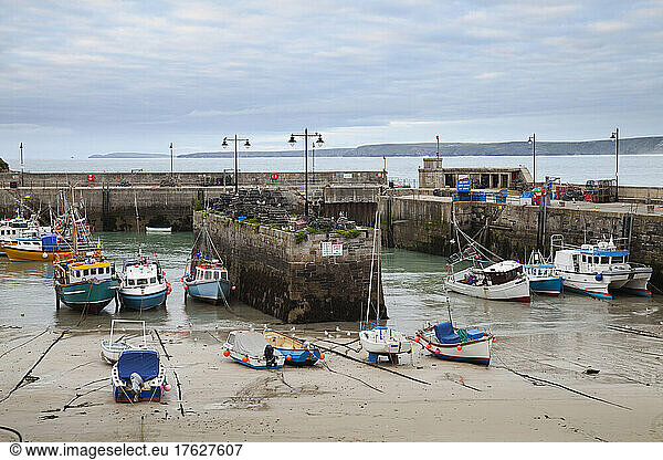 Low tide at a Cornish harbour  sea coast fishing village  boats moored  beached on the sand.