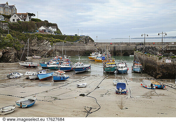 Low tide at a Cornish harbour  sea coast fishing village  boats moored  beached on the sand.