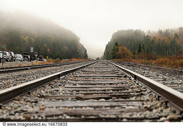 Low vantage point of railroad track leading to foggy mountain opening.