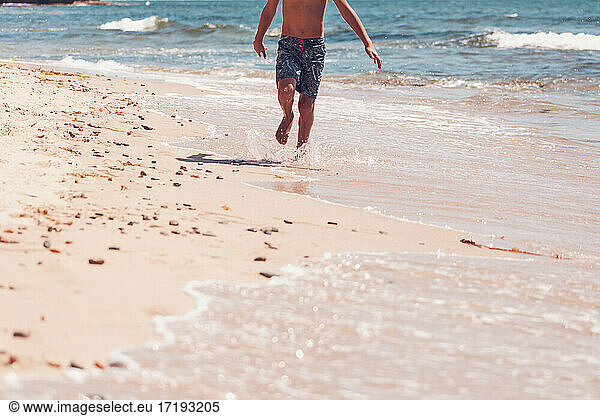 Lower body - boy running on the beach.
