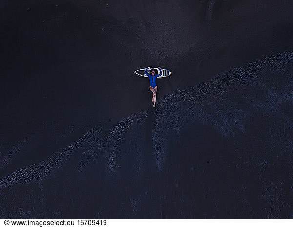 Luftaufnahme einer jungen Frau mit Surfbrett am Strand  Strand von Kedungu  Bali  Indonesien