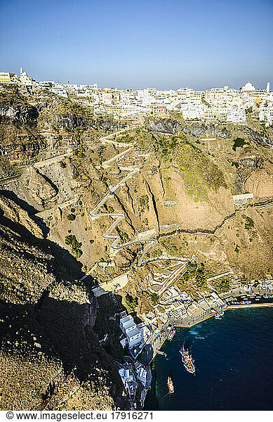 Luftaufnahme einer Stadt an der Spitze einer steilen Klippe auf der Insel Egeo und der gewundene Weg zu den Häusern von der Landestelle an der Küste.