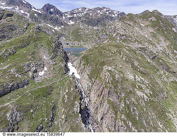 Luftaufnahme eines Alpensees und eines schneebedeckten Wasserfalls