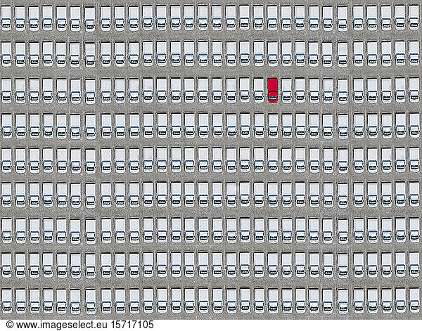 Luftaufnahme eines einzelnen roten Autos  das inmitten nur weißer Autos geparkt ist