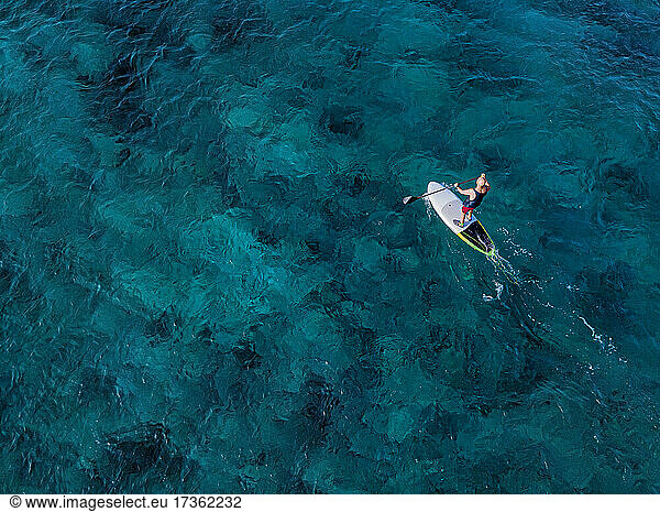 Luftaufnahme eines Mannes beim Paddeln im blauen Wasser des Nord Male Atolls