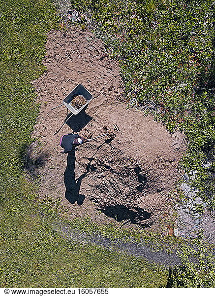 Luftaufnahme eines Mannes  der Sand auf eine Schubkarre lädt