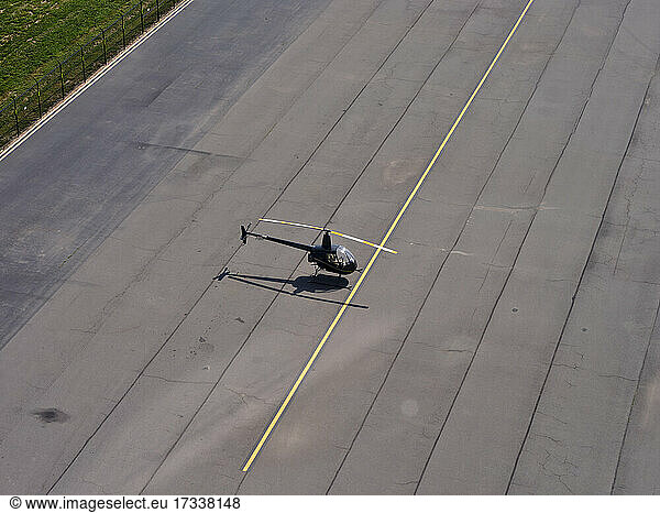 Luftaufnahme eines Robinson R22-Hubschraubers  der in der Mitte einer leeren Start- und Landebahn steht